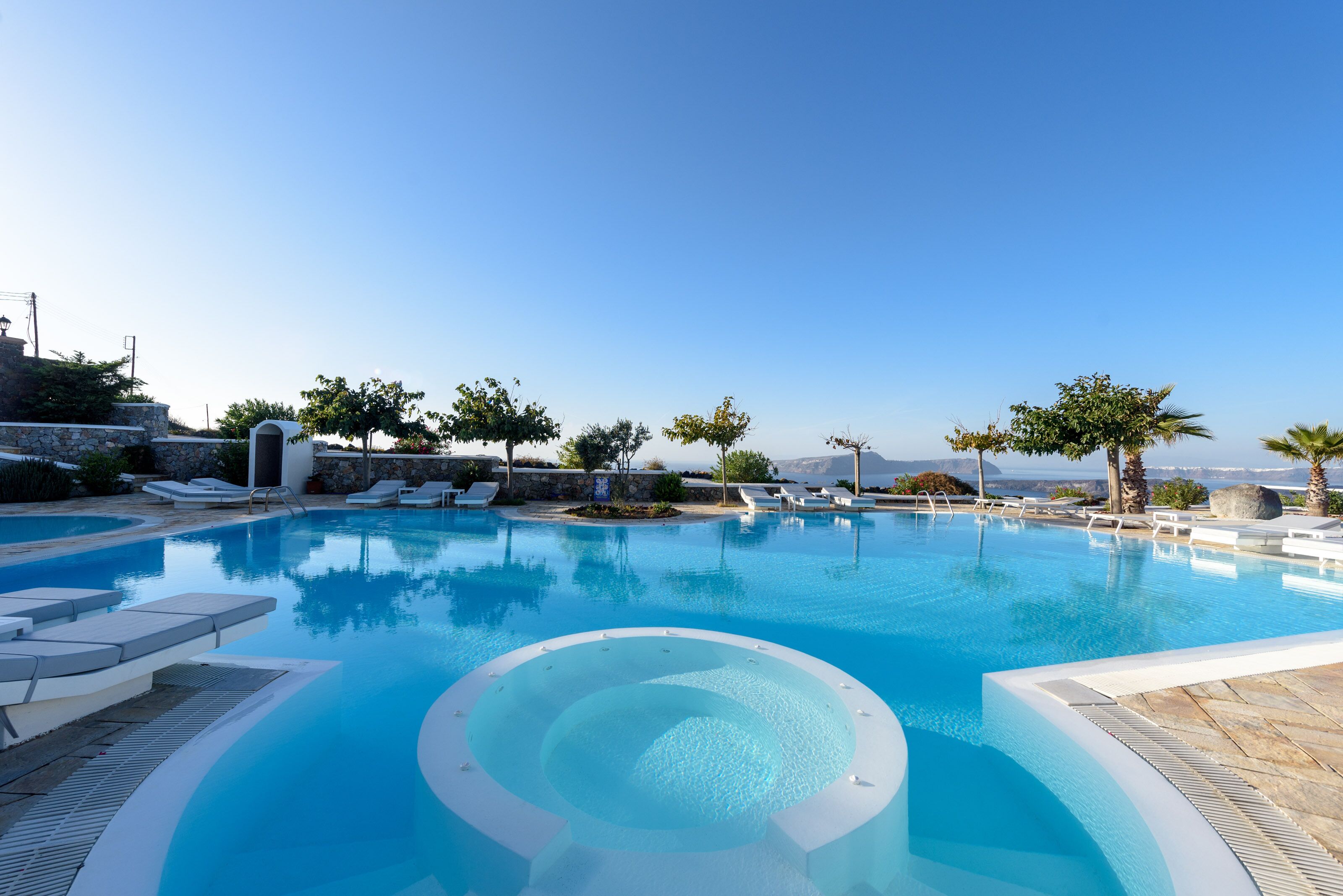 Ein klarer, blauer Swimmingpool mit Liegestühlen und einer Steinsäule.