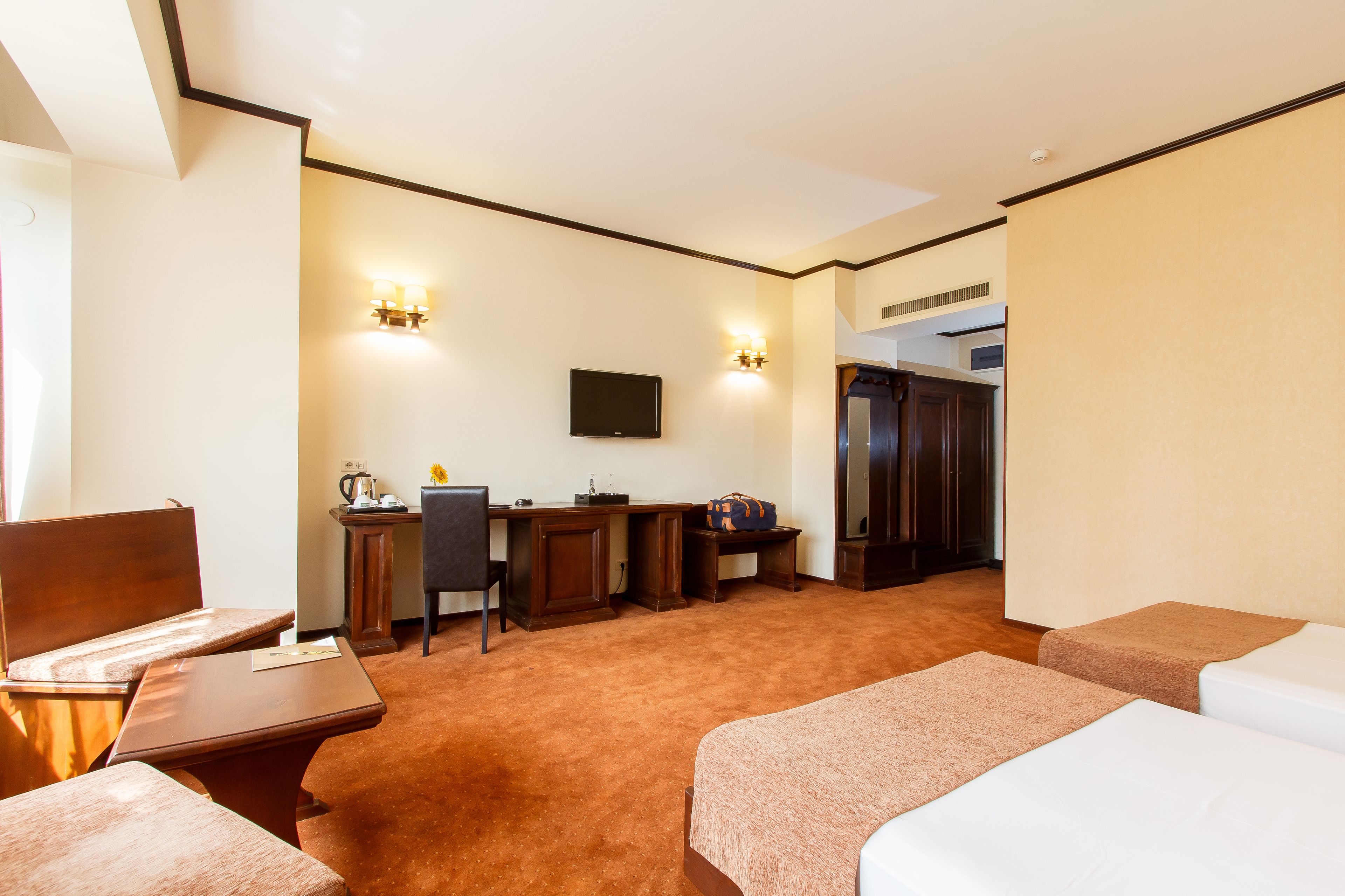 Habitación de hotel con cama, escritorio, silla, televisión y kitchenette.