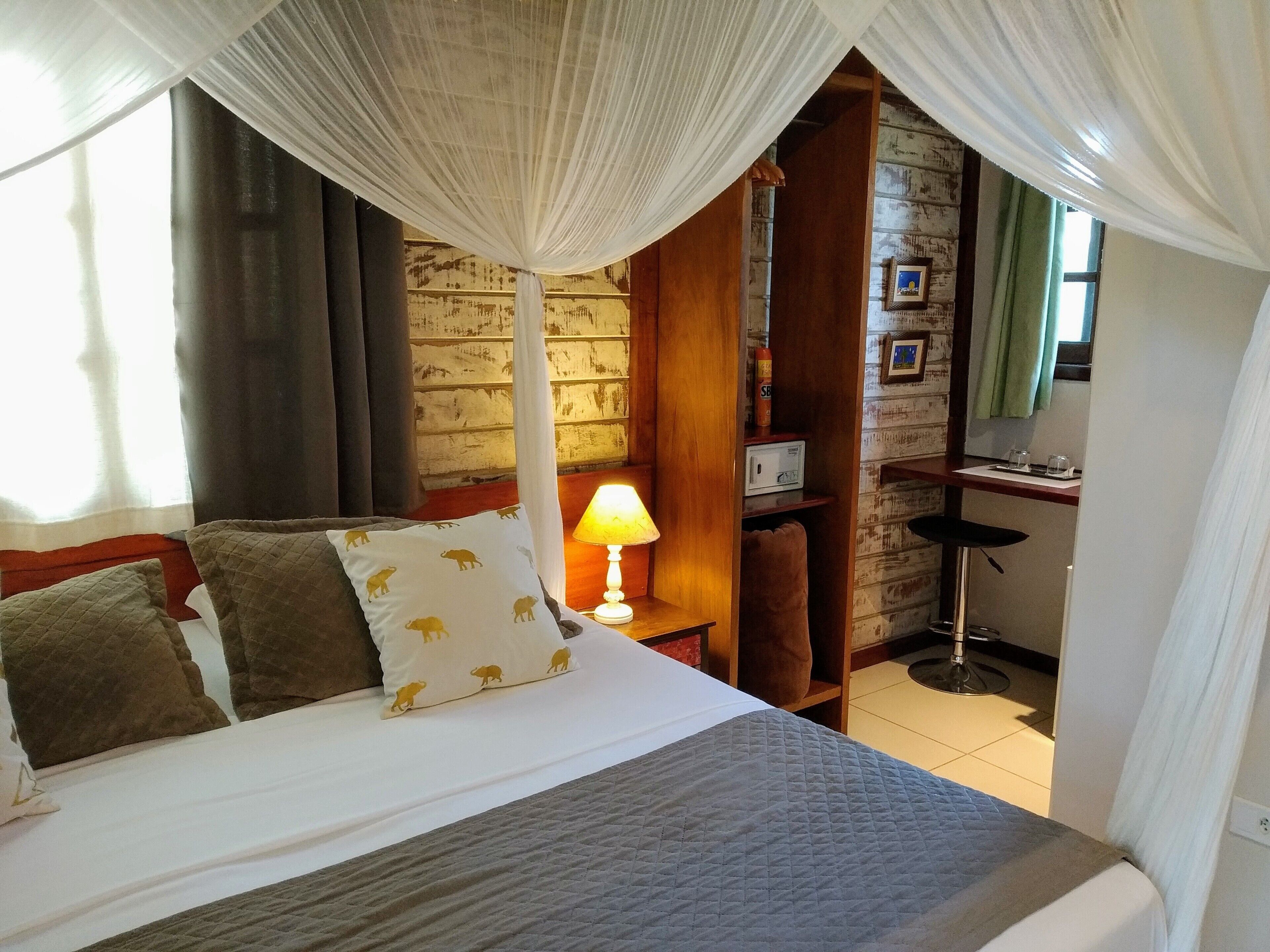 A bed with a white and grey quilt, a bedside lamp, and a wooden nightstand.