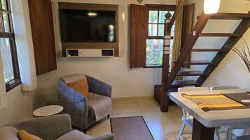 A living room with a sofa, armchair, TV, and a table with a placemat.