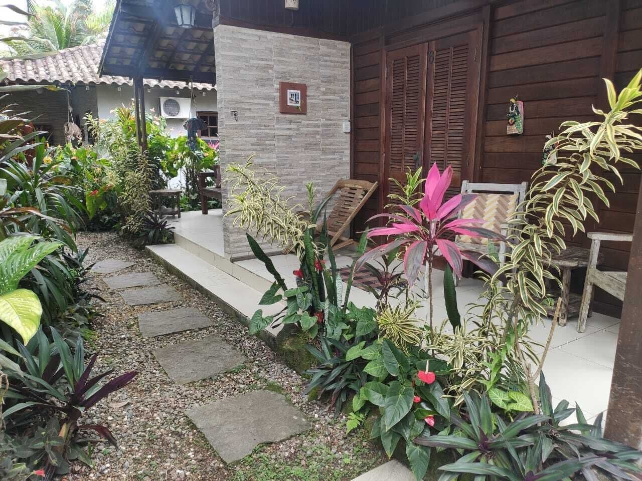 Un jardín con diversas plantas y un edificio de madera con techo de tejas.