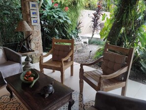 Un espacio al aire libre acogedor con dos sillas de madera, una mesa con un frutero y una lámpara.