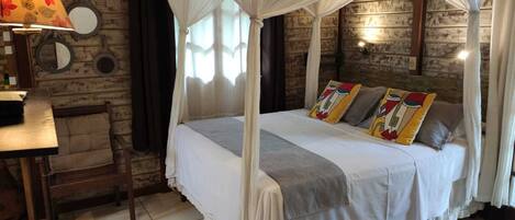 Una habitación con una cama con dosel, una pared de madera, una mesita con una lámpara y una silla.