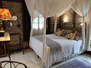 Una habitación con una cama con dosel, una pared de madera, una mesita con una lámpara y una silla.
