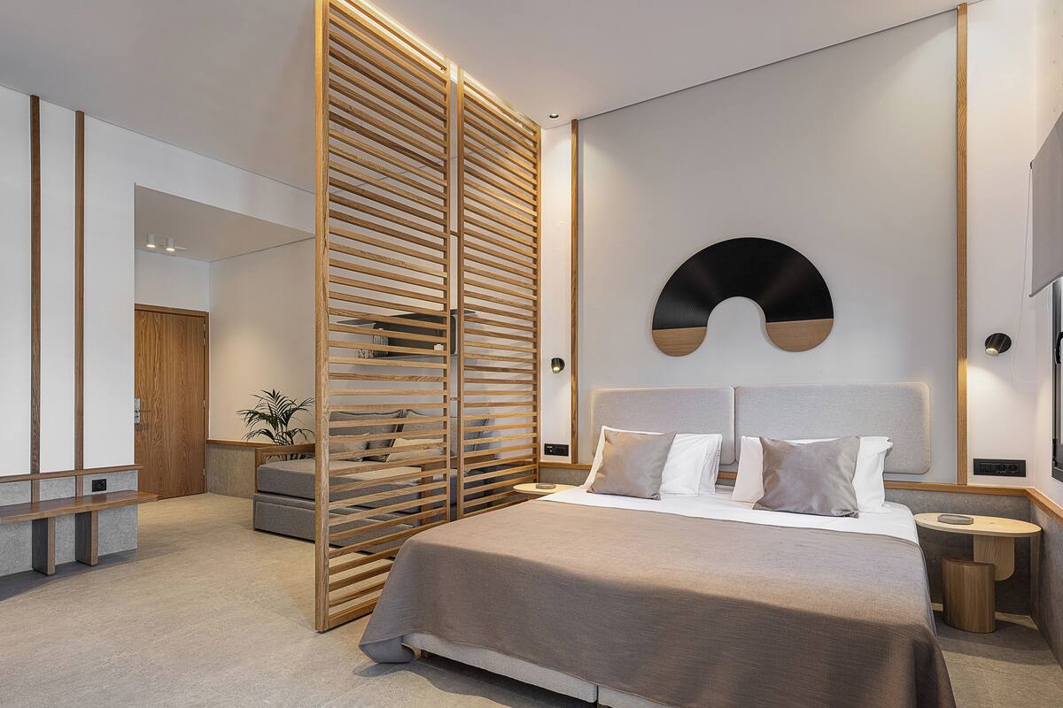A modern bedroom with a bed, wooden slats, a round wall decoration, and a nightstand.