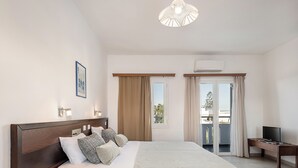 Habitación de hotel con una cama grande, mesitas de noche, televisor y aire acondicionado.
