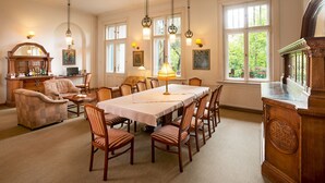 Un comedor con una mesa larga, sillas y lámparas colgantes.