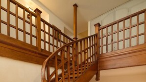 Una escalera de caracol de madera con barandilla, que conduce a un piso superior.