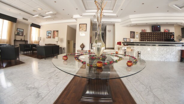 A spacious lobby with a glass-top table, a reception desk, and a seating area with chairs. - La Maison Hotel Petra (Wadi Musa)