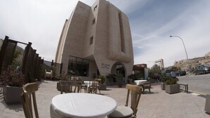 A modern building with a unique architectural design, featuring a curved facade and a prominent entrance. - La Maison Hotel Petra (Wadi Musa)