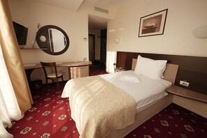 Une chambre d’hôtel équipée d’un lit, d’un bureau, d’une chaise, d’une télévision et d’un miroir.