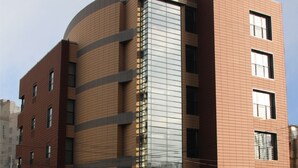 Un hotel moderno con fachada curva, múltiples ventanas y un letrero que indica que es el Hotel Berthelot.