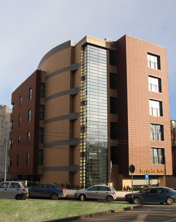 Un hôtel moderne à la façade incurvée, doté de nombreuses fenêtres et d’une enseigne indiquant qu’il s’agit de l’« hôtel Berthelot ».