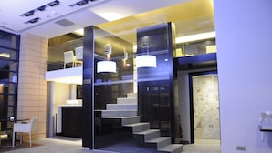 Un interior moderno con una escalera, divisiones de vidrio e iluminación contemporánea.