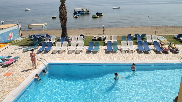 A pool area with lounge chairs and a view of the sea.