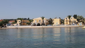 A coastal hotel with multiple buildings, a sandy beach, and palm trees.