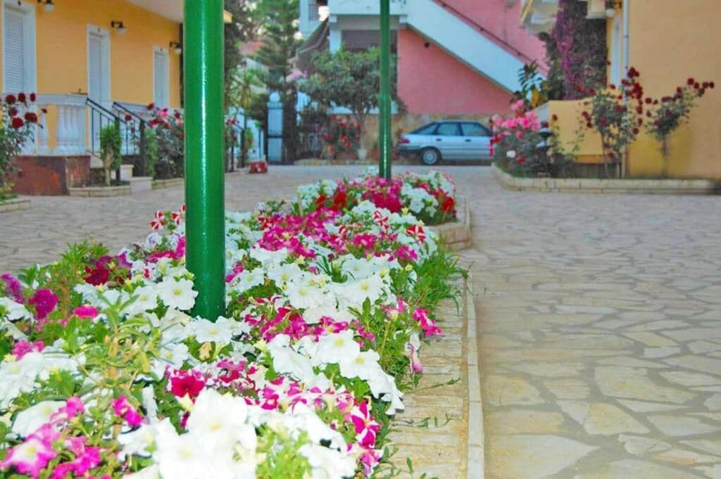 Un sendero pavimentado bordeado por macizos de flores blancas y rosas.