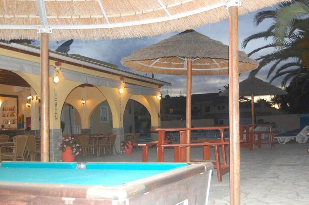 A pool area with umbrellas, lounge chairs, and a building with arches and lights.