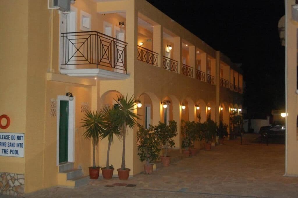 Un hotel con varios balcones, plantas en macetas y un cartel que prohíbe la entrada de arena a la piscina.