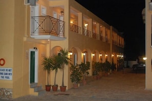 Un hotel con varios balcones, plantas en macetas y un cartel que prohíbe la entrada de arena a la piscina.
