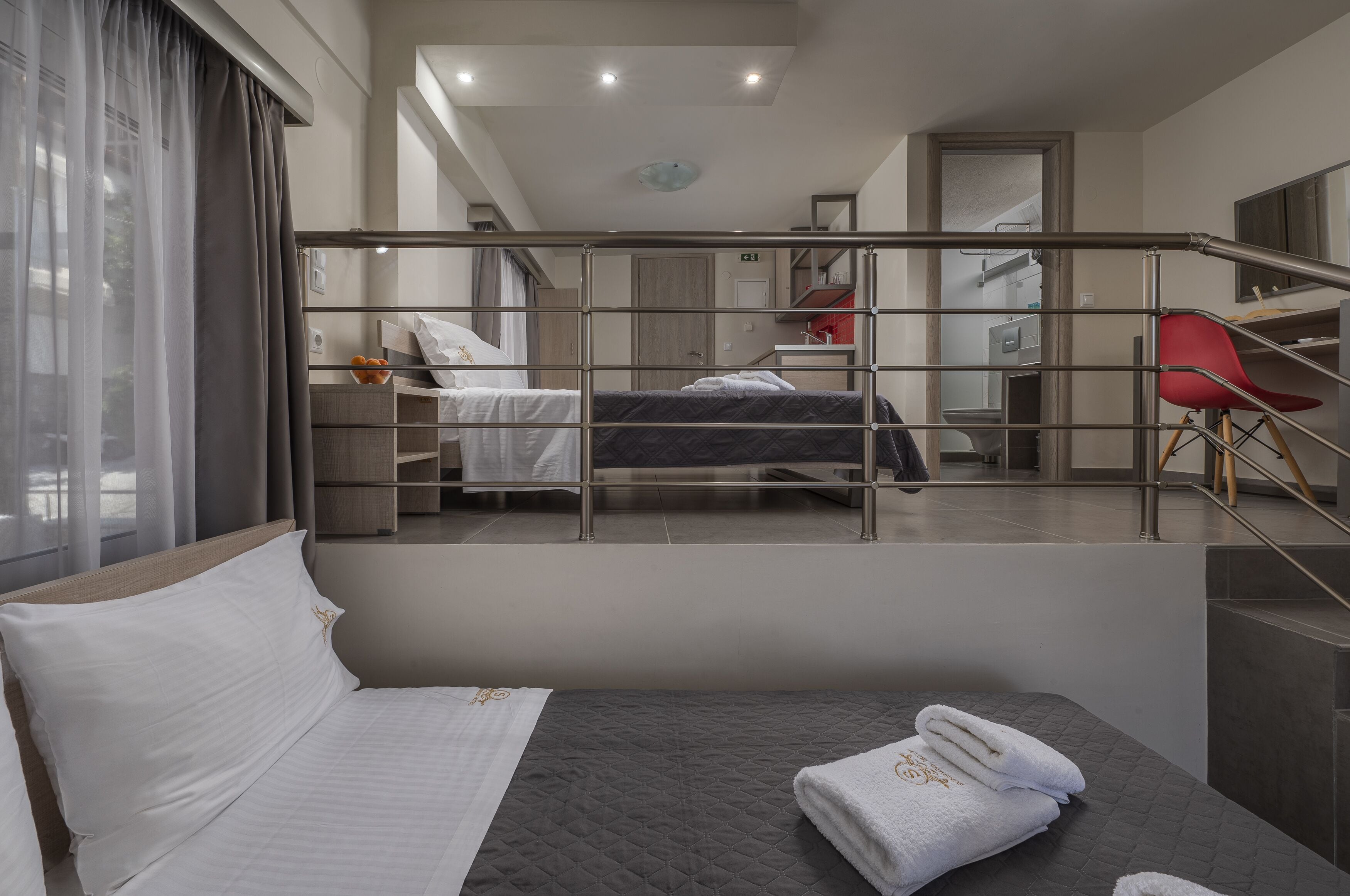 Une chambre d’hôtel moderne équipée d’un lit, d’un bureau, d’une chaise et donnant sur le couloir.