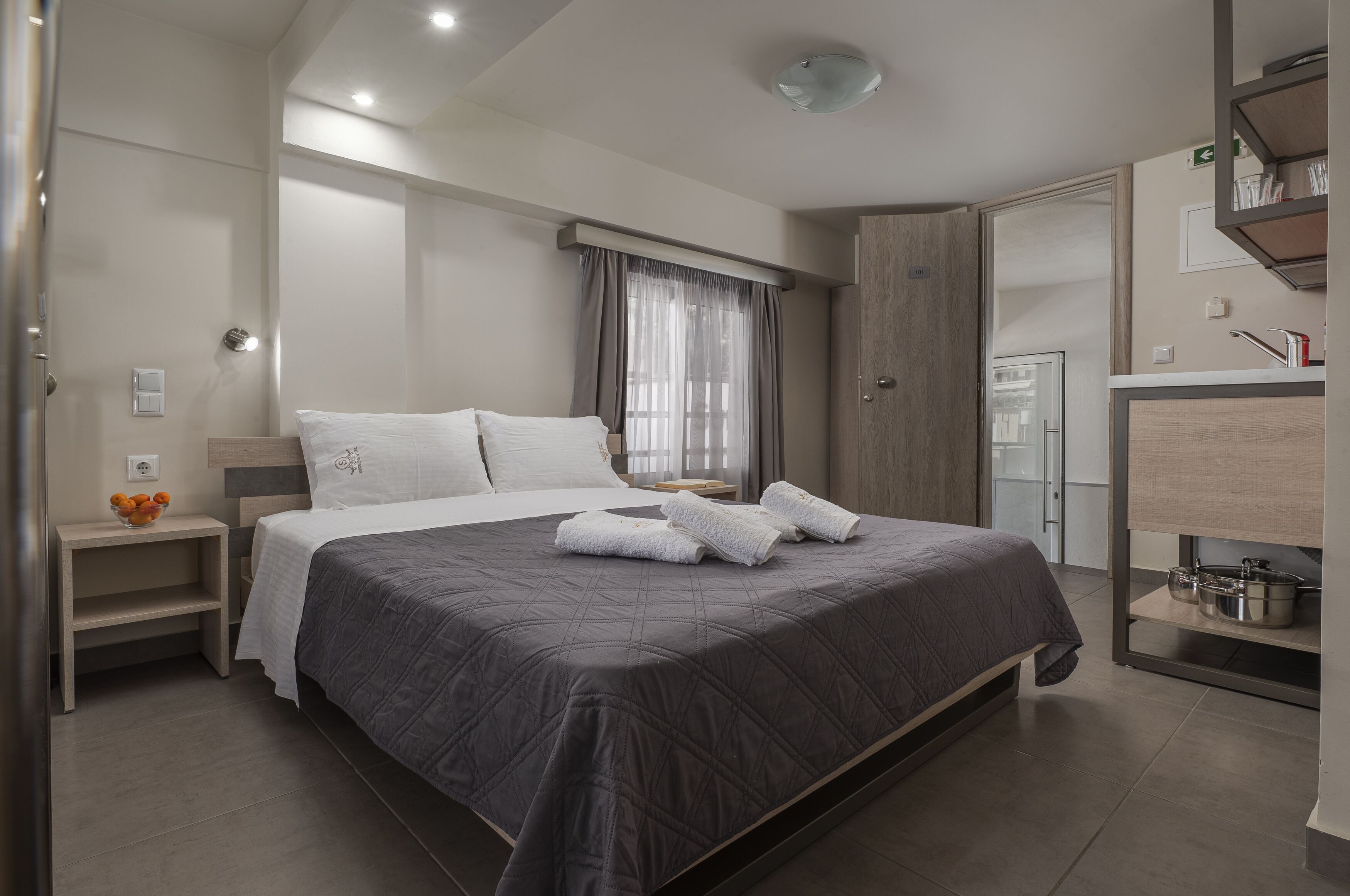 Ein modernes Schlafzimmer mit einem großen Bett, Nachttischen, einem Kleiderschrank und einem durch eine offene Tür einsehbaren Badezimmer.
