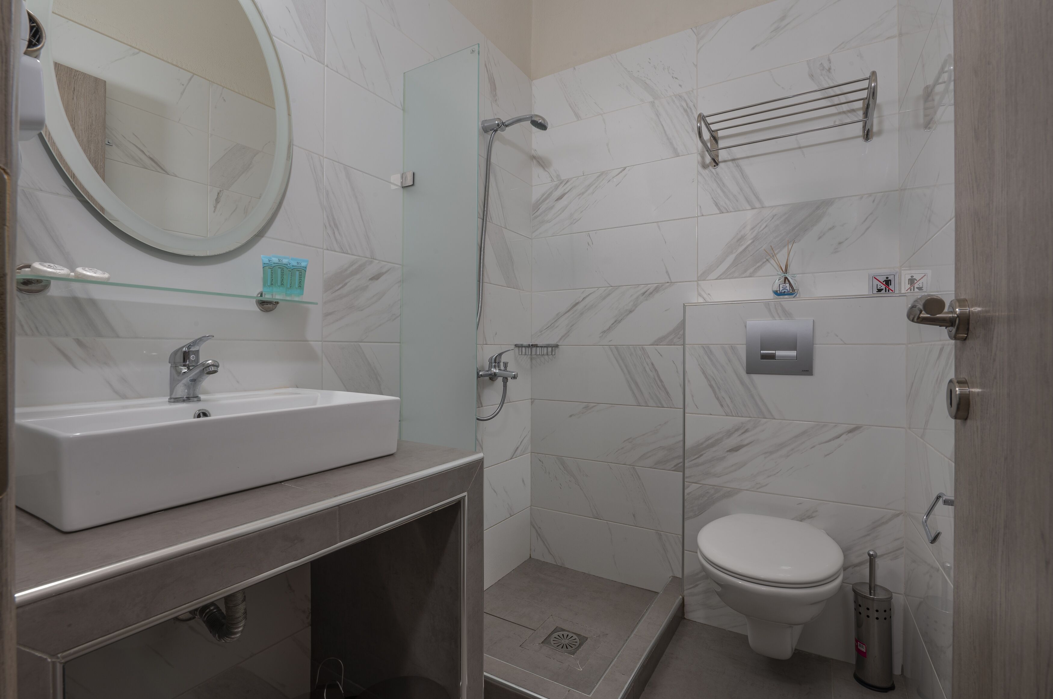 Een moderne badkamer met wastafel, spiegel, douche en toilet.