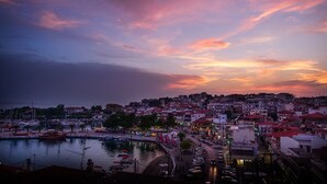 Un pueblo costero al atardecer con un puerto deportivo, edificios y una carretera que lleva al pueblo.