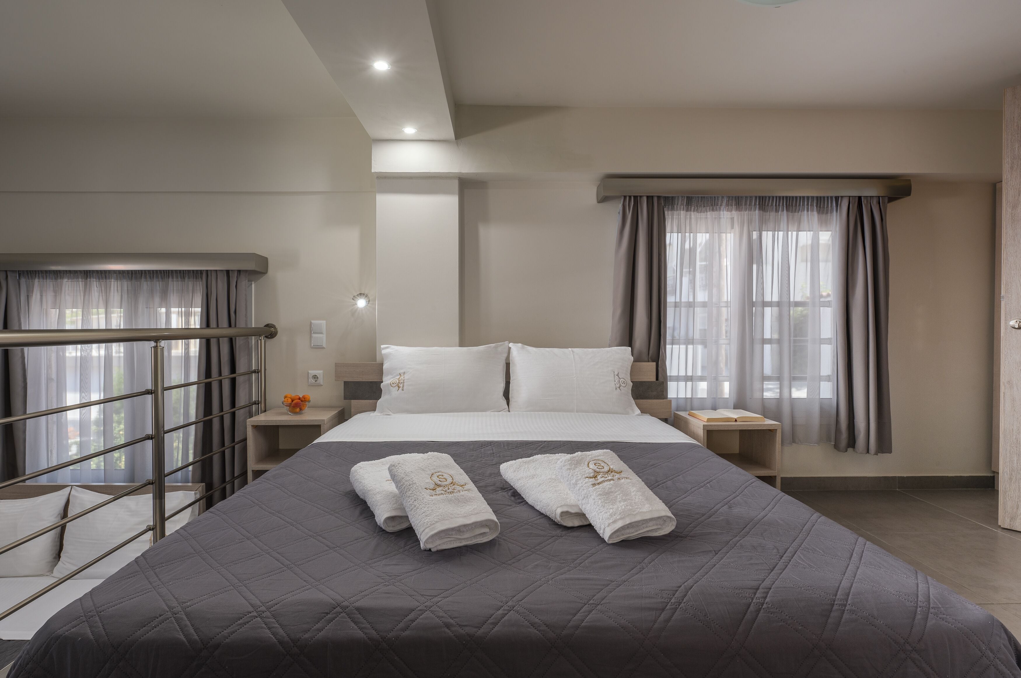 Habitación de hotel con cama, dos mesitas de noche, una ventana con cortinas y vista al exterior.