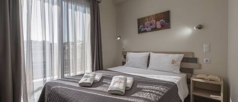 A modern hotel room with a large bed, a bedside table with a lamp, and a painting on the wall.