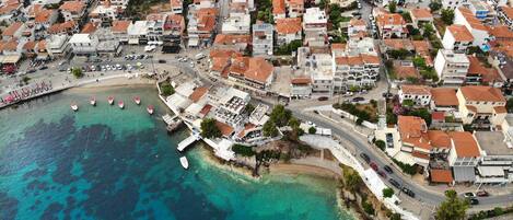 An aerial view of a coastal town with a beach, buildings, and boats.
