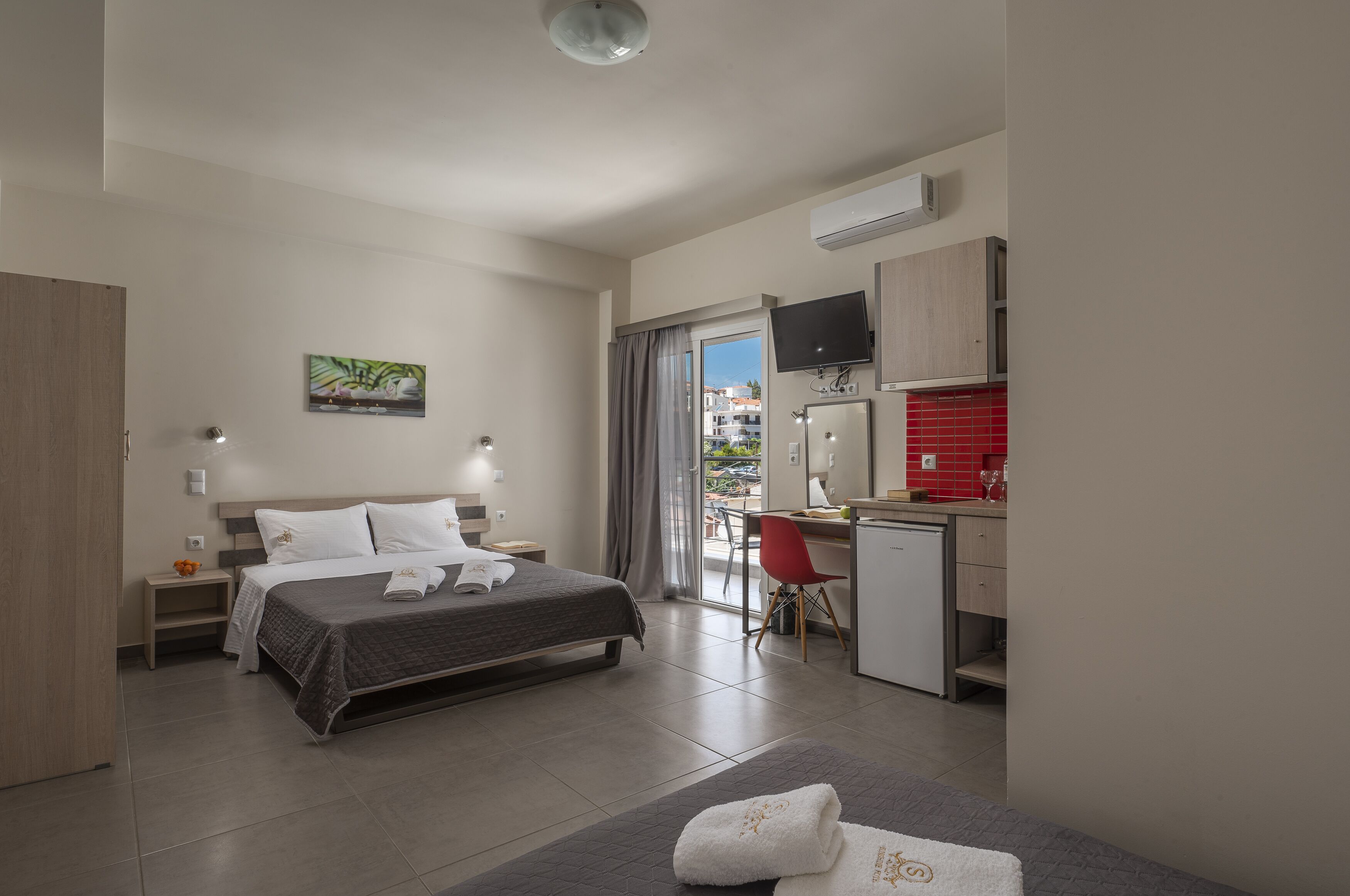 A modern hotel room with a bed, bedside table, and a desk area.