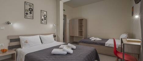 A hotel room with a large bed, a smaller bed, a desk, a chair, and a wardrobe.
