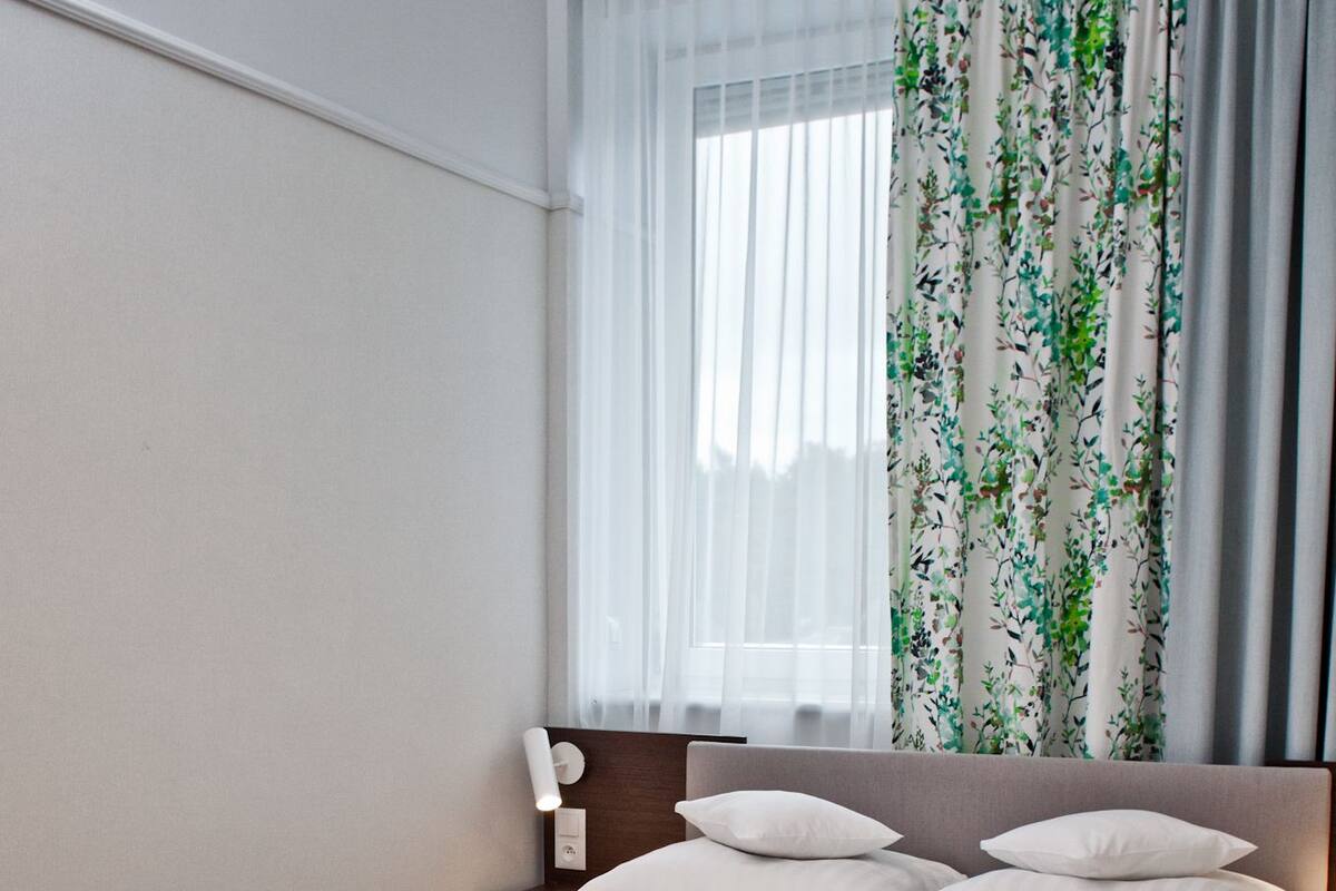 Een net opgemaakt bed met een beige sprei, een houten hoofdbord en witte kussens.