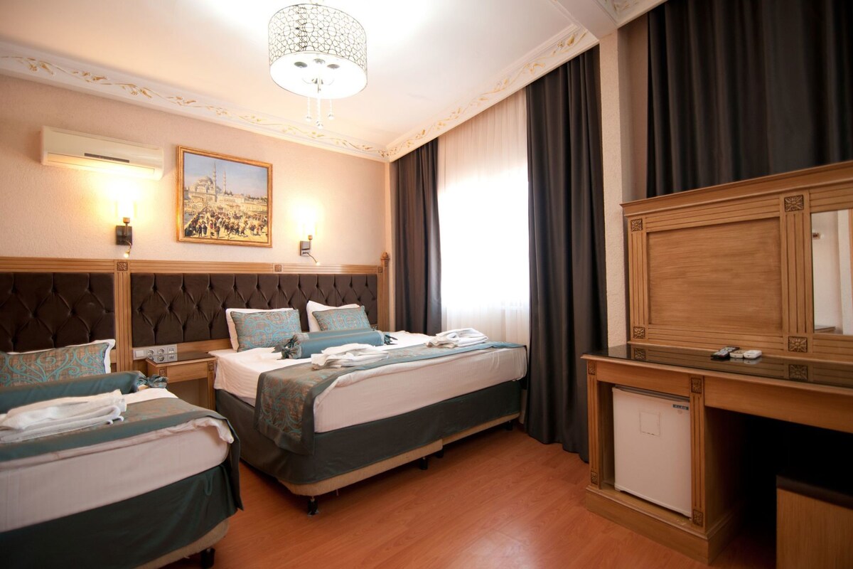 Una habitación de hotel con dos camas, un escritorio de madera, un televisor y un cuadro en la pared.