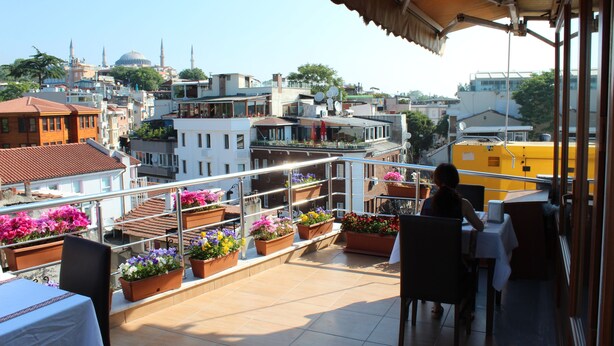 A rooftop terrace with outdoor seating, potted plants, and a view of the cityscape including a mosque. - Blue Tuana Hotel (Istanbul)