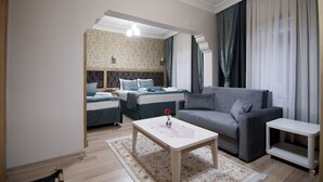 A modern hotel room with a sofa, a small table, a bed with a headboard, and a large window with curtains. - Blue Tuana Hotel (Istanbul)