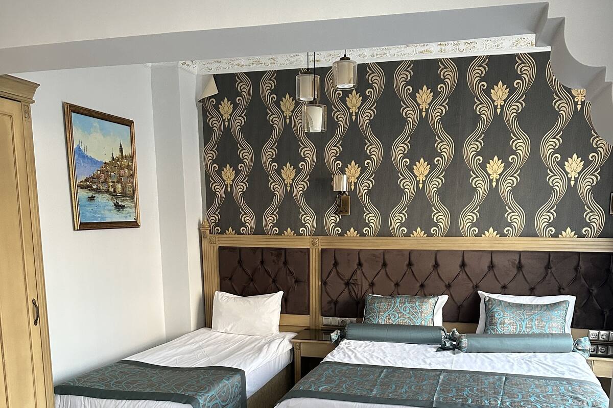 A hotel room with two single beds, a double bed, a sofa, and a wooden wardrobe.