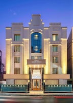 A modern hotel with a central entrance, large windows, and a prominent sign.