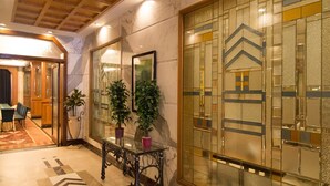 A lobby with marble flooring, a glass partition with geometric patterns, and a wooden ceiling. - Sarovar Portico Kalupur Ahmedabad (Ahmedabad)