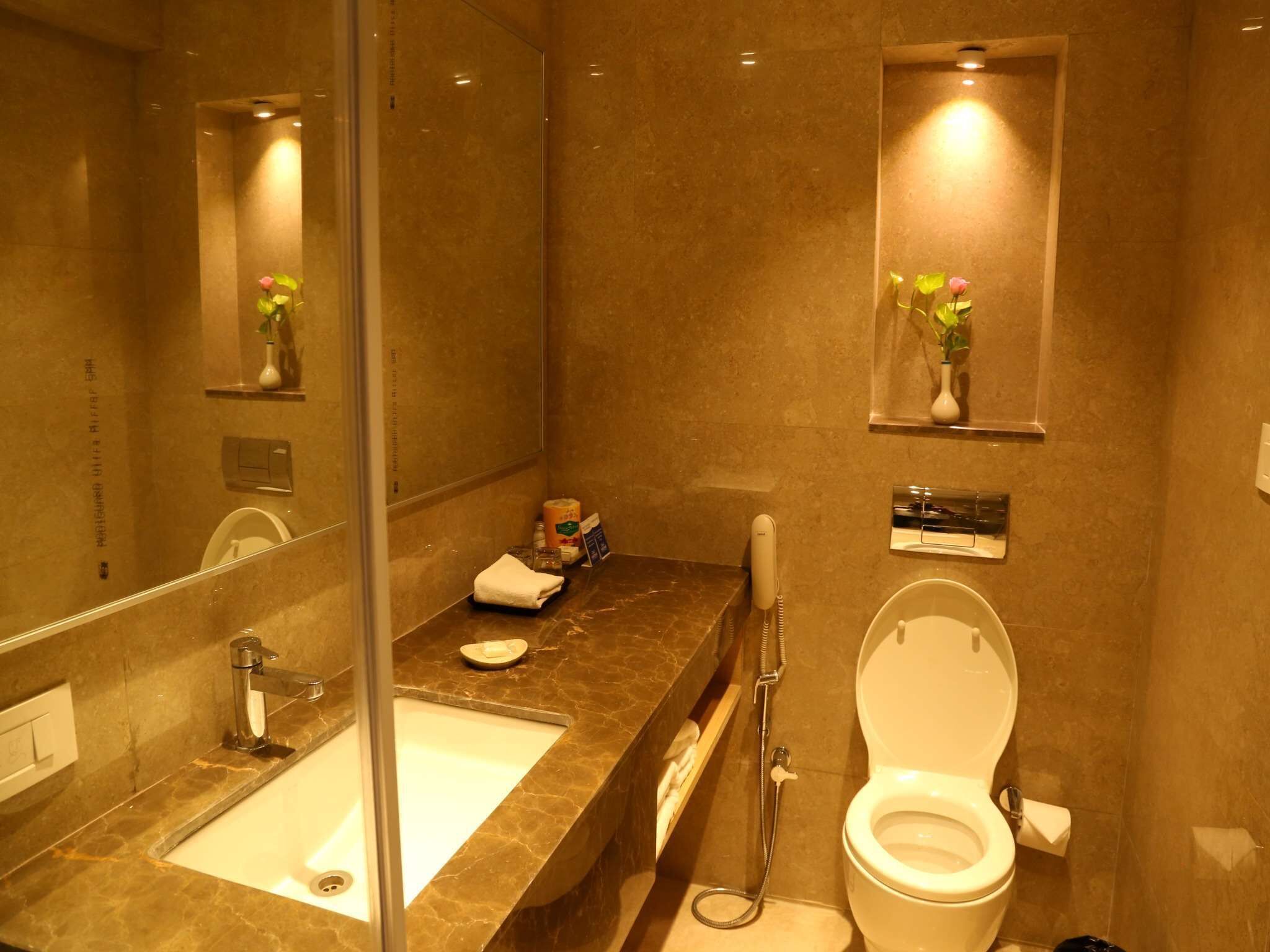 A bathroom with a marble sink, a toilet, and a mirror.
