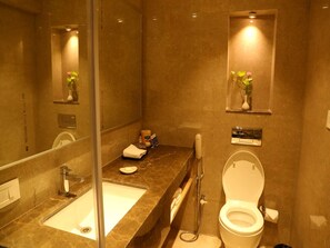 A bathroom with a marble sink, a toilet, and a mirror.