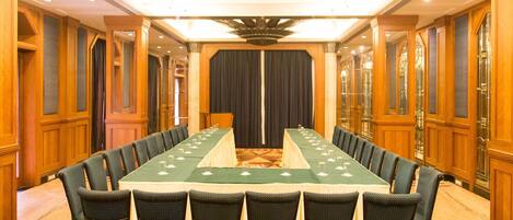 A conference room with a long table, chairs, and a stage.