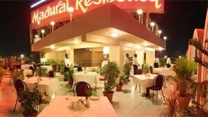 An outdoor restaurant with tables and chairs, potted plants, and a sign reading "Madurai Residences". - Madurai Residency (Madurai)