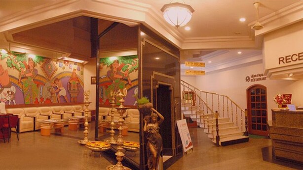 A hotel reception area with a mural, seating, a reception desk, and a staircase. - Madurai Residency (Madurai)