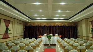 A conference room with rows of chairs, a stage with a table and flowers, and a red carpet. - Madurai Residency (Madurai)
