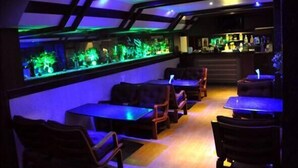 A dimly lit bar area with a large aquarium, seating, and a bar counter. - Madurai Residency (Madurai)
