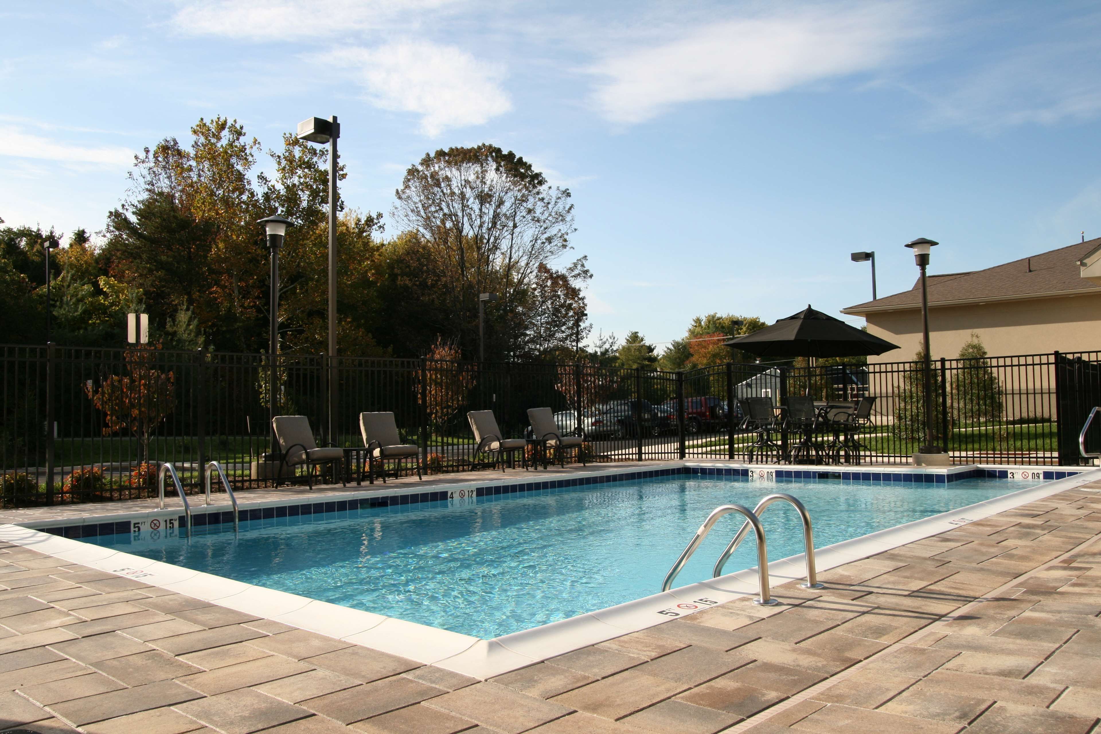 A rectangular swimming pool with a tiled edge, surrounded by a brick deck.