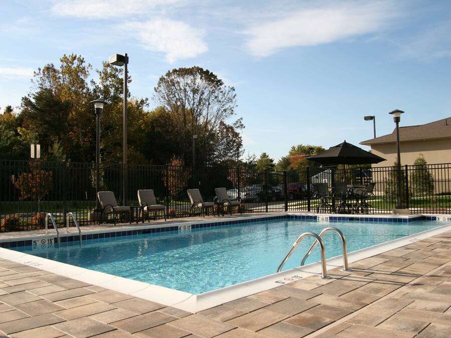 Una piscina rectangular con borde de azulejos, rodeada por un patio de ladrillo.