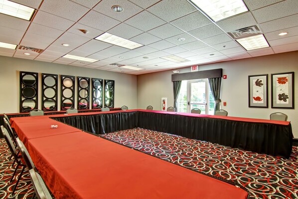 A conference room with a long table, chairs, and a red carpet.